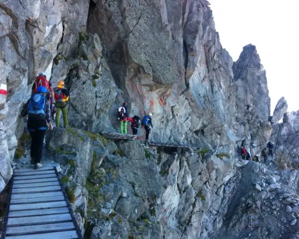 Escursionisti su un sentiero attrezzato, un'avventura di trekking in Adamello tra rocce e passerelle di legno.
