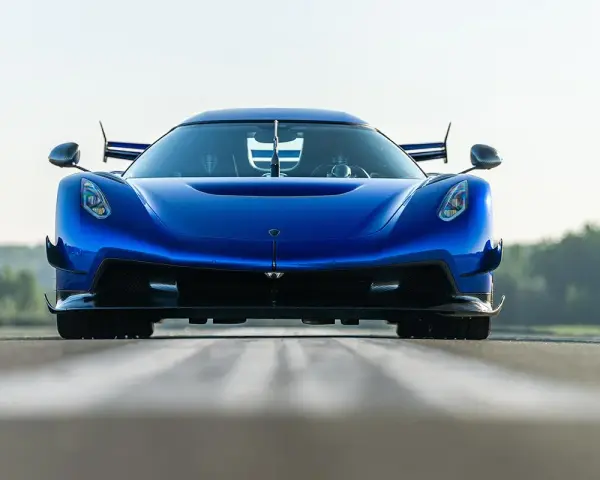 Niebieski Koenigsegg Jesko Attack z agresywnym przednim splitterem i spojlerami, gotowy do ataku na torze.