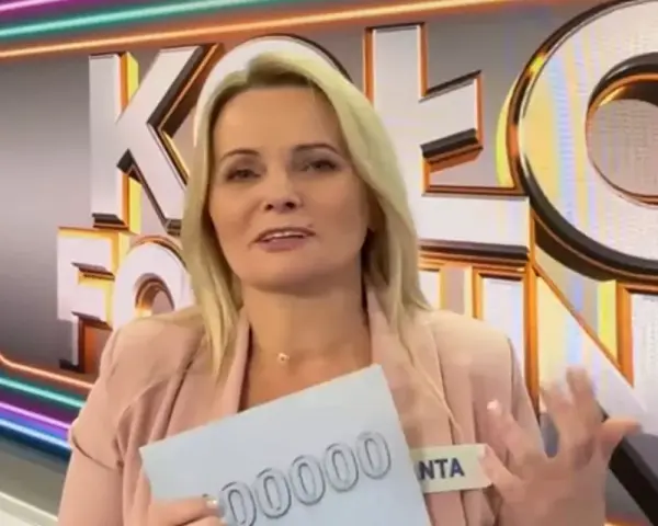 Kobieta z Koła Fortuny trzyma kartę z napisem "00000", zastanawiając się, co daje złota karta w kole fortuny.
