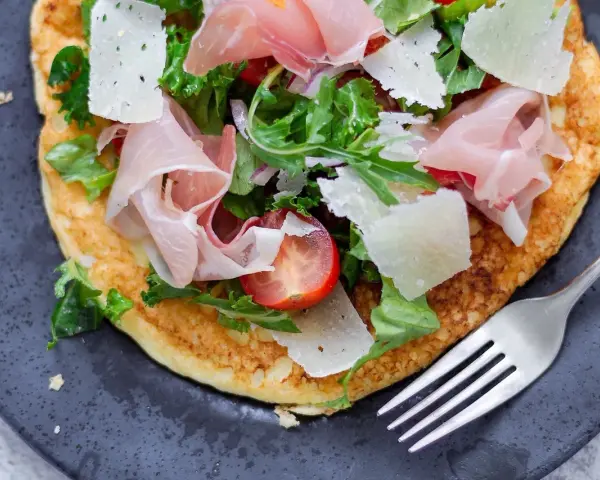 Pyszny przepis na omlet na słono z szynką parmeńską, parmezanem, pomidorkami i rukolą. Idealny na szybki obiad lub kolację.