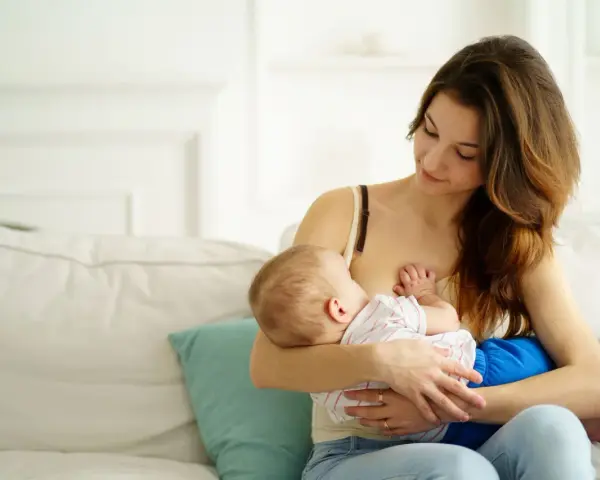 Ciepła chwila karmienia piersią. Mama z miłością patrzy na swoje dziecko, wspierając naturalną laktację.