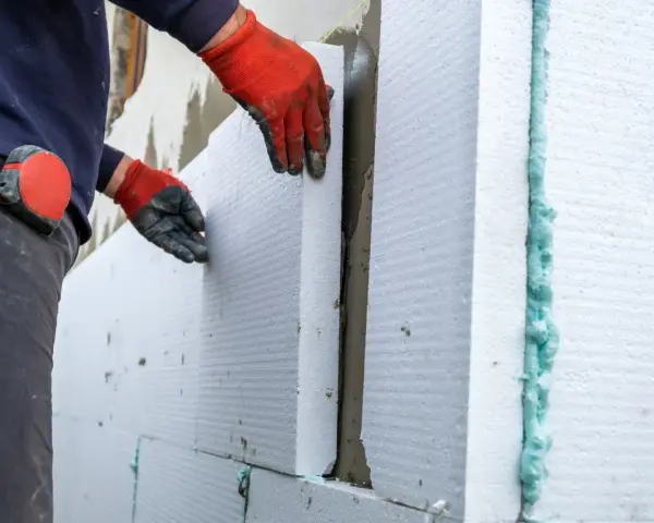 Operaio posa pannelli isolanti per cappotto termico, attenzione alle fughe e alle soglie per evitare ponti termici.