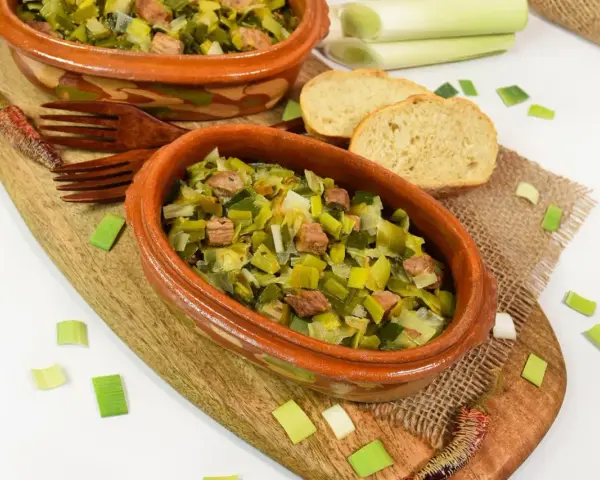 Zwei Terrinen mit Lauchgemüse und Fleischstücken, serviert mit Brot. Ein leckeres Beispiel für Lauch Rezepte.