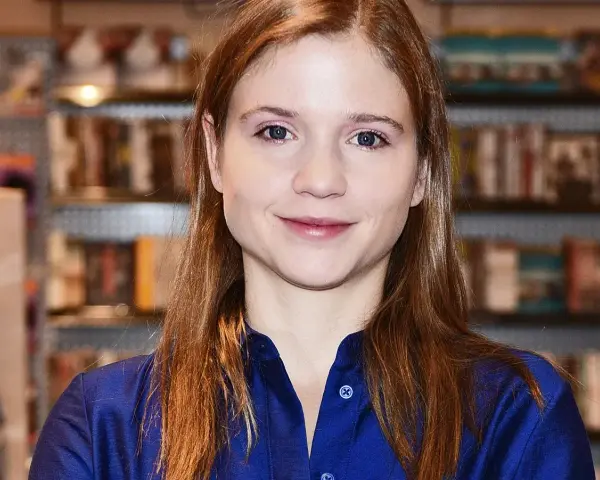 Eliza Rycembel, uśmiechnięta, w niebieskiej bluzce, na tle regałów z książkami. Jej życie prywatne jest tematem zainteresowania.