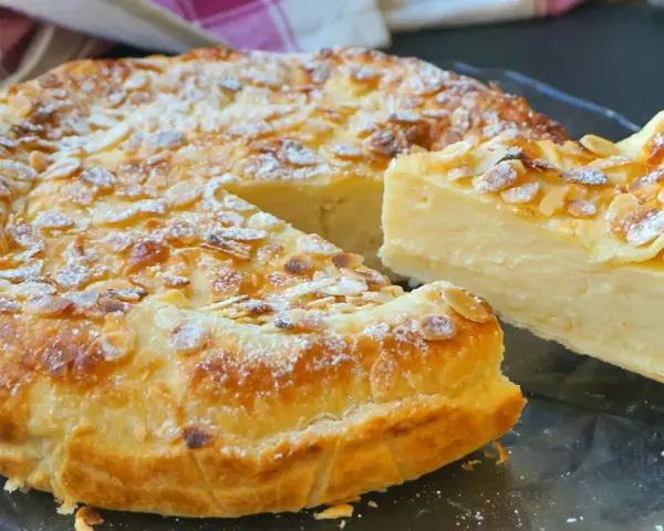 Tarta de hojaldre y crema pastelera, cubierta de almendras laminadas y espolvoreada con azúcar glas. ¡Un postre irresistible!