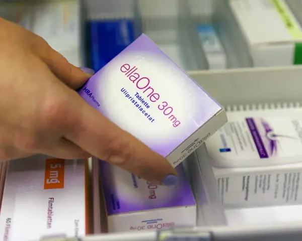 Hand greift nach ellaOne 30mg Tablette. Informationen zu ellaOne Nebenwirkungen sind auf der Packung zu finden.