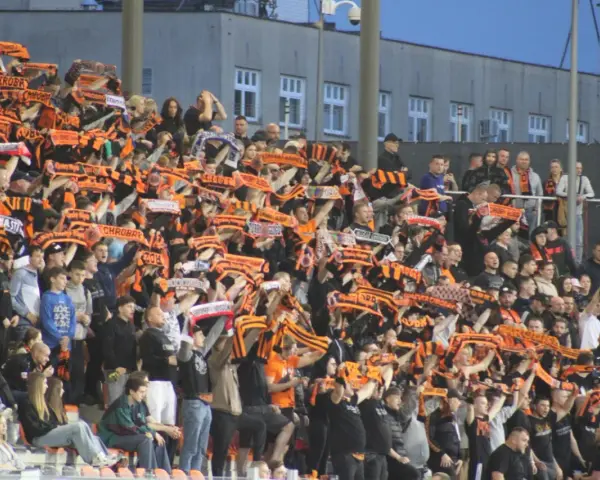 Tłum kibiców na stadionie z szalikami w barwach pomarańczowo-czarnych. Widać napisy "Chrobry" i "Chrobry Głogów".