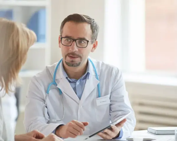 Arzt erklärt Patientin Ergebnisse, vielleicht den lipase wert, auf einem Tablet.