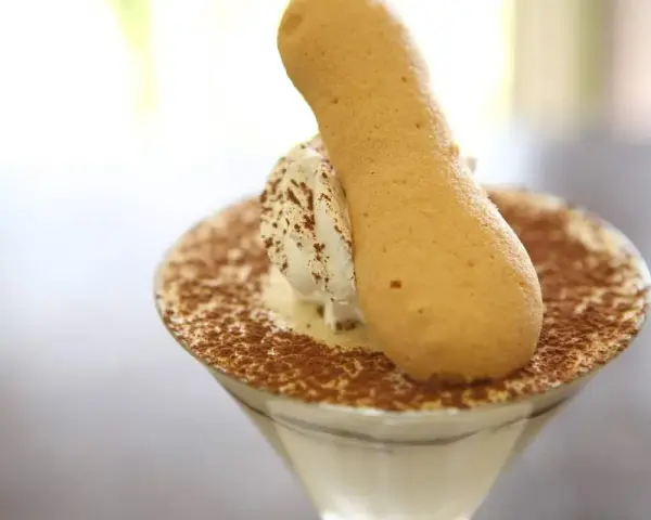Pyszne tiramisu w kieliszku, posypane kakao, z biszkoptem. Idealne, gdy szukasz, czym zastąpić amaretto.