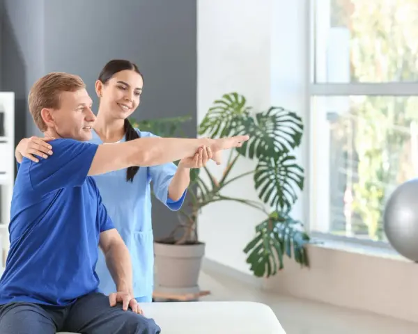 Ein Physiotherapeut unterstützt einen Patienten bei der Armbewegung.
