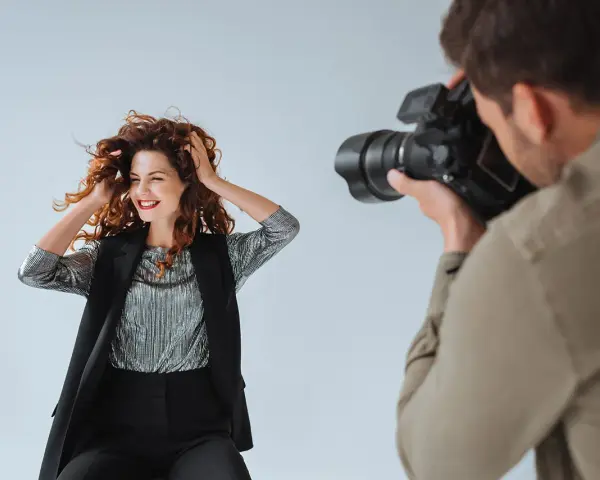 Modelka z burzą rudych włosów pozuje do zdjęcia. Fotograf robi jej zdjęcie. To sesja TFP, co to znaczy?
