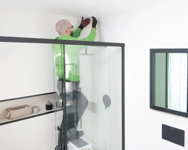 Hombre instala extractor baño en el techo.