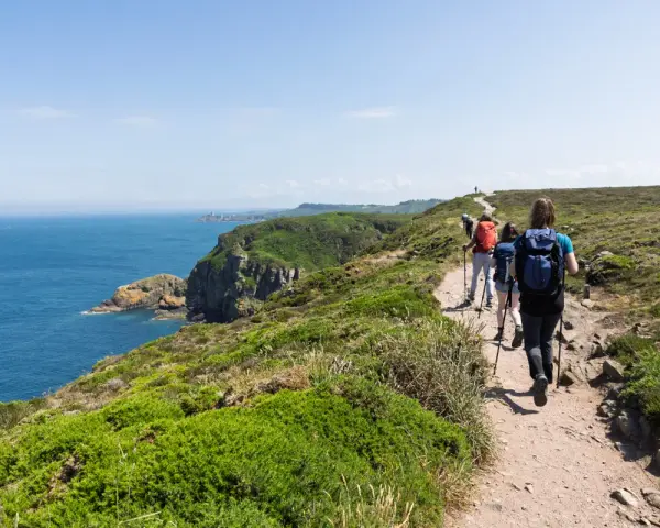 Randonneurs sur le sentier côtier GR34, profitant de la vue sur la mer et les falaises. La distance semble longue, mais le paysage est magnifique.