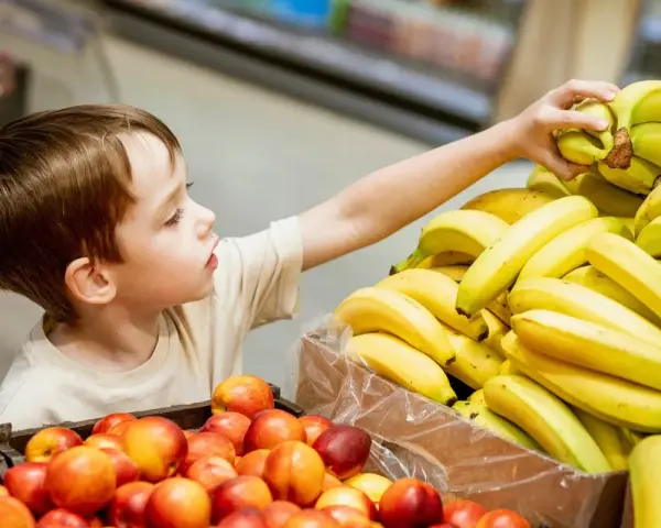Chłopiec sięga po banana. Co zrobić, gdy dziecko kradnie w sklepie? Rozmowa i nauka uczciwości to klucz.