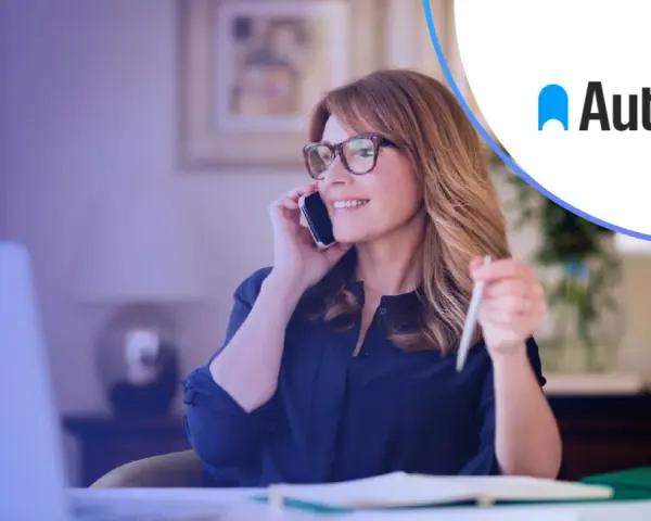 Kobieta rozmawia przez telefon, trzymając długopis. Logo Autopay obok. Dowiedz się, autopay co to jest.