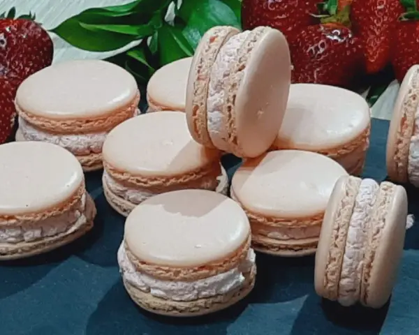 Delikatne makaroniki na mące migdałowej lub kokosowej, z kremowym nadzieniem i świeżymi truskawkami w tle.