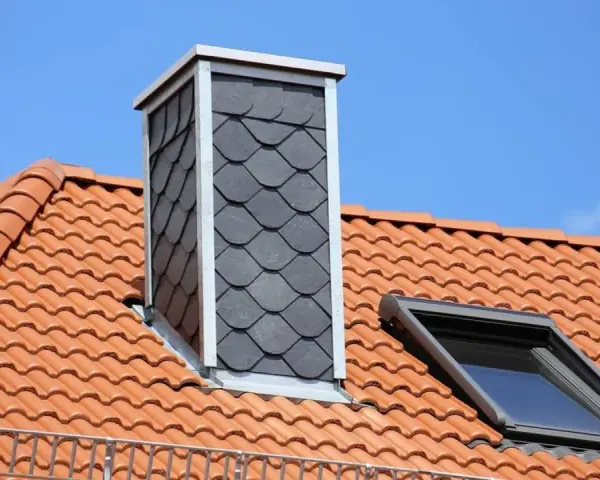 Schornstein verkleiden innen mit Schieferplatten. Dachziegel und Dachfenster sind zu sehen.