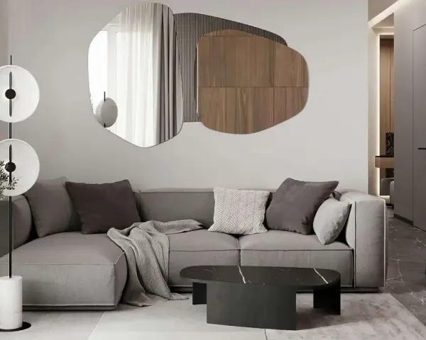 Nowoczesny salon z szarą sofą, geometrycznym lustrem i designerską lampą.