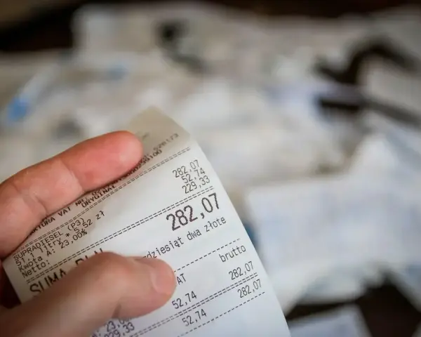 Dłoń trzyma paragon z widoczną kwotą 282,07 zł.