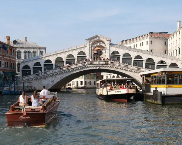 Gondola e vaporetti navigano sul Canal Grande sotto il maestoso Ponte di Rialto, un'icona di Venezia.