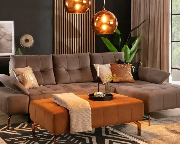 Elegancki salon z sofą w kolorze taupe, który jest pięknym odcieniem brązu z szarym akcentem. Wygodny narożnik i pufa tworzą przytulną przestrzeń.