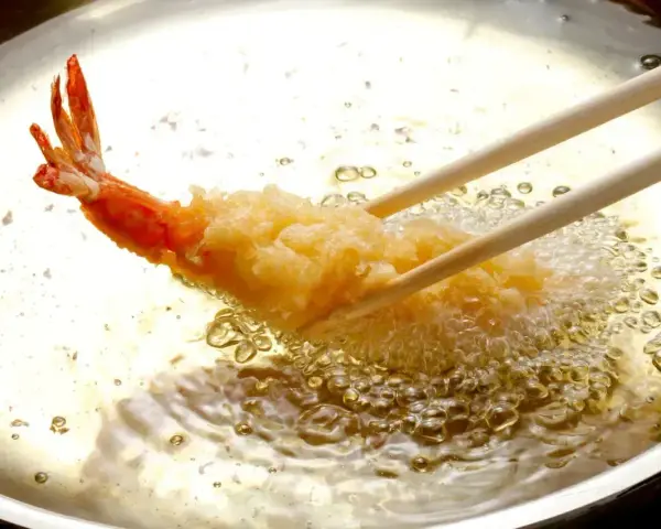 Krewetka w chrupiącej panierce panko smaży się na złoto w gorącym oleju.