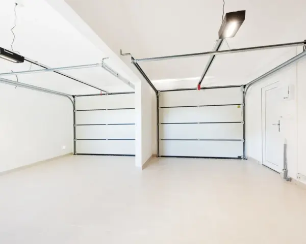 Dos puertas de garaje se abren a un espacio limpio y moderno, listo para pintar el garaje original.