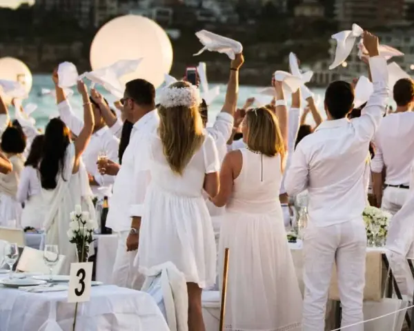 Festa in bianco: tutti vestiti di bianco per un evento elegante sulla spiaggia. Un'atmosfera magica con palloncini luminosi e tavoli apparecchiati.