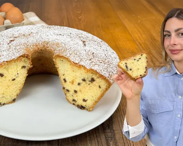 Un soffice ciambellone al bicchiere con gocce di cioccolato, spolverato di zucchero a velo, pronto per essere gustato.