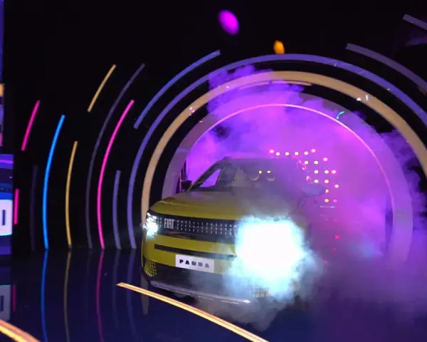 Żółty Fiat Panda wyjeżdża z dymu i świateł w kole fortuny.