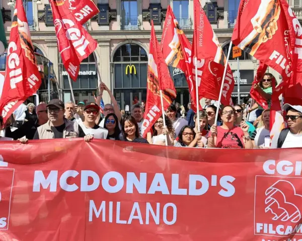 Manifestanti con bandiere rosse chiedono un miglior stipendio McDonald's a Milano.