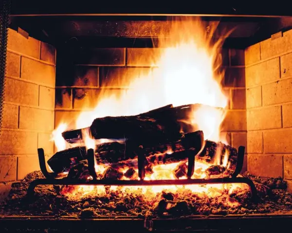 Legna che arde in un camino, con fiamme vivaci e un buon tiraggio presa aria camino che alimenta il fuoco.