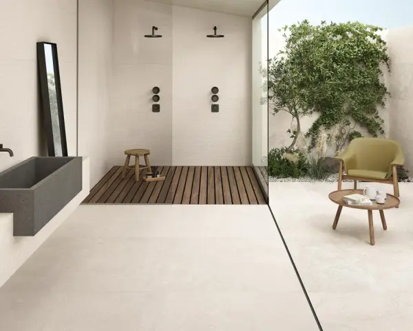 Un bagno moderno con vasca in pietra, doccia a filo pavimento e un'area relax esterna. Il pavimento casa mare crea un'atmosfera rilassante.