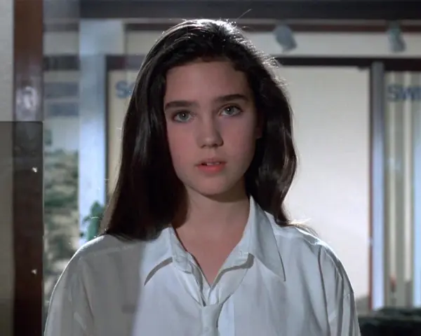 Młoda Jennifer Connelly w białej koszuli, z charakterystycznym spojrzeniem, jak z jej wczesnych filmów.