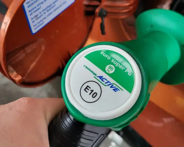 Dłoń trzyma zielony pistolet dystrybutora z napisem "euro super Pb 95 ACTIVE E10". To benzyna e10.