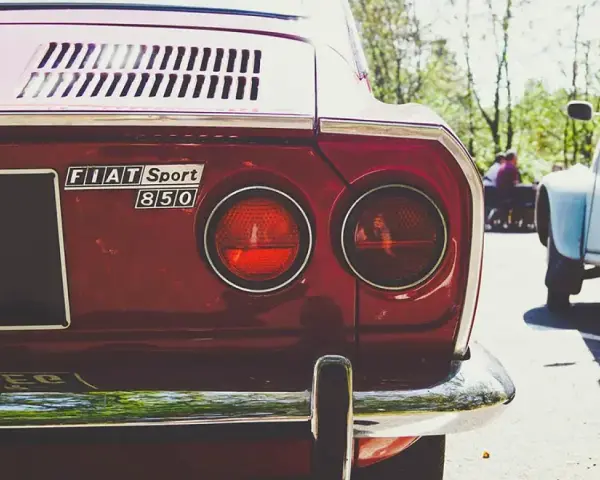 Dettaglio posteriore di una Fiat Sport 850 rossa, con i suoi iconici fanali rotondi. Un pezzo di storia automobilistica, un vero art 102 cds.
