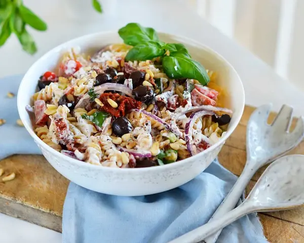 En härlig italiensk pastasallad med rotfrukter, oliver, soltorkade tomater och pinjenötter, toppad med färsk basilika.