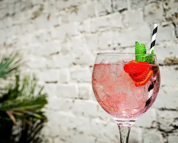 Orzeźwiający pink gin z lodem, truskawką i miętą, idealny na letnie popołudnie.