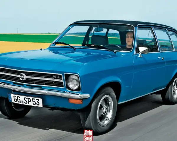 Niebieski Opel Ascona w wersji kombi jedzie po drodze, za nim pola i niebo.