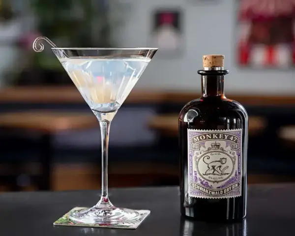 Klasyczny gin martini przepis z Monkey 47. Elegancki kieliszek z drinkiem i butelka ginu na blacie.