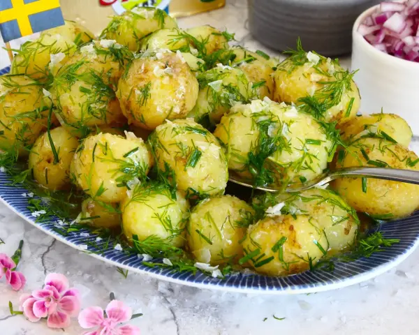 Njut av nykokt färskpotatis med dill och gräslök, en klassiker som visar hur kokar man potatis till perfektion. En svensk flagga vajar stolt.