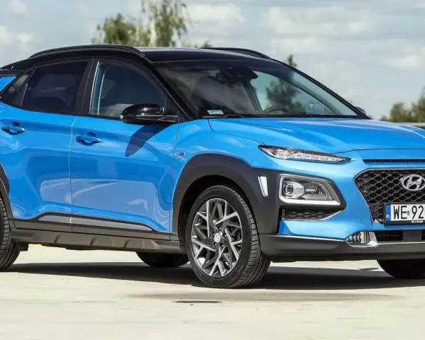 Niebieski Hyundai Kona 2025 z czarnym dachem, zaparkowany na zewnątrz.