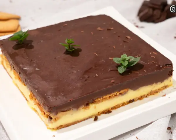 Deliciosa tarta de la abuela con capas de galleta y crema, cubierta de chocolate y decorada con menta fresca.
