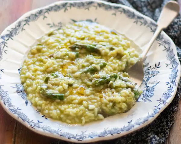 Un cremoso risotto agli asparagi, servito in un piatto decorato, pronto per essere gustato.