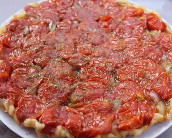 Tarte tatin di pomodorini confit, con cipolle caramellate e erbe aromatiche, un tripudio di sapori mediterranei.