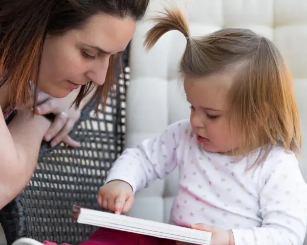 Mama czyta dziecku, a maluch odkrywa świat przez książkę, tworząc własne neologizmy dziecięce.