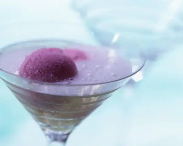 Ein erfrischendes Eis mit Sekt in einem Martiniglas. Die pinke Eiskugel schwimmt in prickelndem Sekt, ein Genuss für heiße Tage.