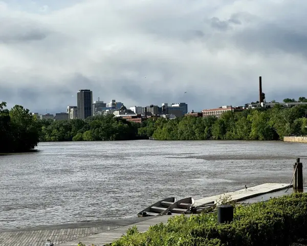 A cloudy sky looms over the Richmond, VA skyline, with the James River in the foreground. This view hints at fun things to do in Richmond, VA, like kayaking or enjoying the riverfront.