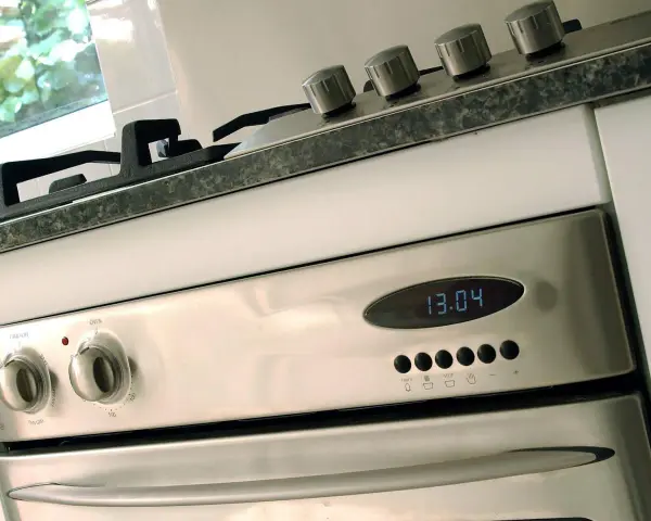 Edelstahl-Backofen mit digitaler Zeitanzeige (13:04). Die Knöpfe für Funktion und Temperatur sind sichtbar. Bereit für den ersten **Backofen einbrennen**.