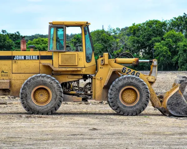 Żółta koparko-ładowarka John Deere 624G gotowa do pracy, wymaga odpowiednich uprawnień do obsługi.